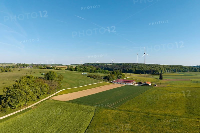 Farm, green fields stretch out under a blue sky, with wind turbines in the distance, near Westerheim, Swabian Alb, Baden-Württemberg, Germany