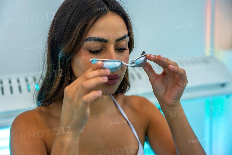 Client preparing for a uv tanning session, holding protective eyewear while getting ready in a beauty salons sunbed area