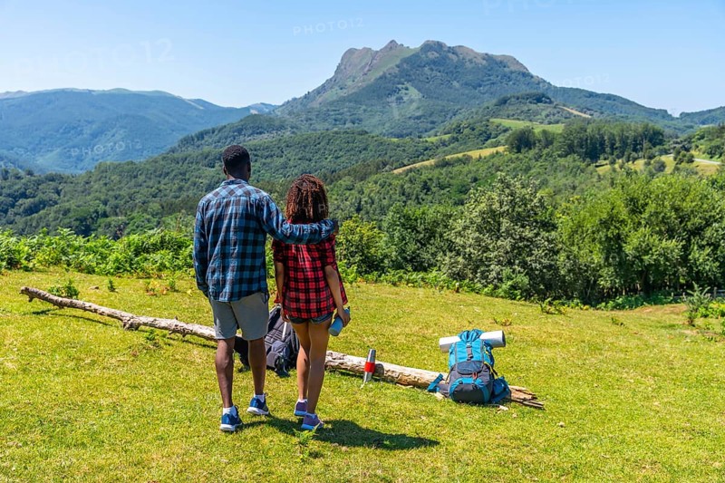 Couple admiring breathtaking mountain landscape during summer hike, enjoying the peace and beauty of nature