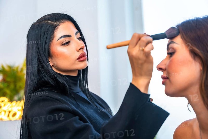 Makeup artist skillfully applying foundation on a client's face in a beauty salon, using a brush with precision and attention to detail