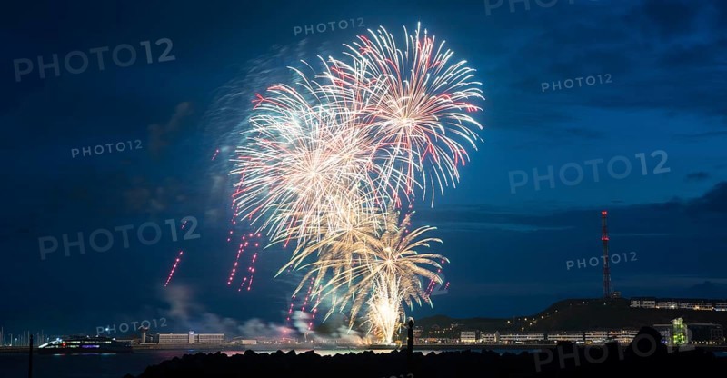 Bright illuminated colours, atmospheric fireworks in red, green and gold, Heligoland island festival, Unterland with inland harbour, jetty and lobster shacks, on the right the Oberland with transmission tower, transmitter, night shot, in front the groyne of the dune, reflecting water of the North Sea, night sky at the island festival, summer, symbolic image also for New Year's Eve, New Year's Eve fireworks, bright, colourful, festive, colourful traces of light, lively glitter, night, Heligoland Island, Schleswig-Holstein, Germany