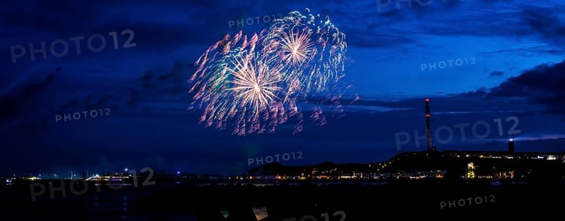 Radiant luminous colours, atmospheric fireworks in red, green and gold, Heligoland island festival, Unterland with inland harbour, jetty and lobster shacks, on the right the Oberland with transmission tower, transmitter and lighthouse, night shot, in front the groynes of the dune, reflecting water of the North Sea, night sky at the island festival, summer, symbolic picture also for New Year's Eve, New Year's Eve fireworks, bright, colourful, colourful traces of light, lively glitter, night, Heligoland Island, Schleswig-Holstein, Germany