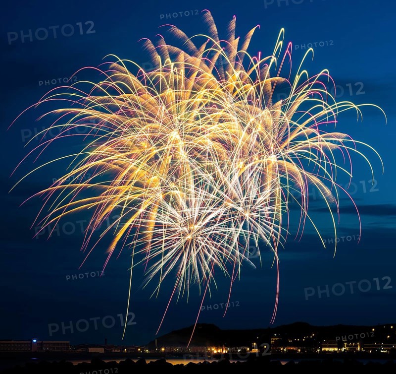 Bright, atmospheric, splendid and intense fireworks display with many illuminated sheaves for the Heligoland island festival in red and gold over the nocturnal lowlands and the inland harbour, with the tetrapod dune platforms and the reflecting waters of the North Sea in front, Night sky at the island festival in summer, symbolic image also for New Year's Eve, New Year's Eve fireworks, bright, colourful, many colourful traces of light, sparks, lively glitter, night, Heligoland Island, Schleswig-Holstein, Germany