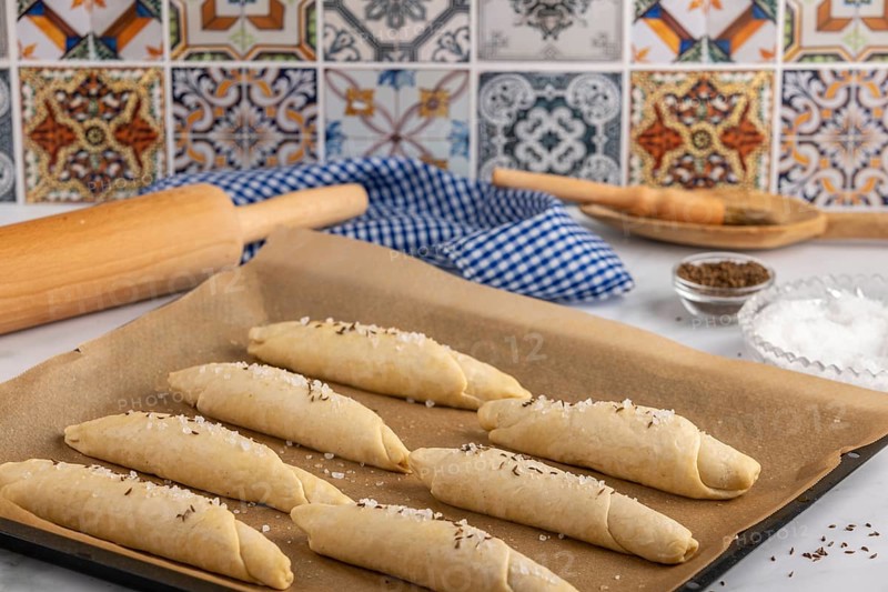 Sprinkle the raw salt sticks with salt and caraway seeds on a baking tray