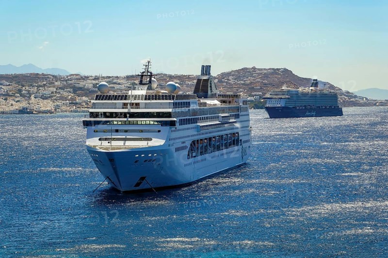 Mykonos, Cyclades, Greece - Cruise ships MEIN SCHIFF 5 and MSC LIRICA are located in the bay off Mykonos City. Old town with windmills. Cruise ships bring tourists to shore