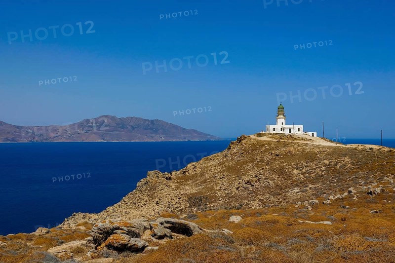 Mykonos, Cyclades, Greece - The Armenistis lighthouse in the north of the island is a landmark and a popular destination for tourists. In the back is the island of Tinos