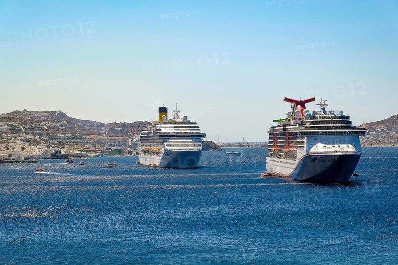 Mykonos, Cyclades, Greece - cruise ships CARNIVAL MIRACLE and COSTA FORTUNA are located in the bay off Mykonos City. Old town with windmills. Cruise ships bring tourists to shore