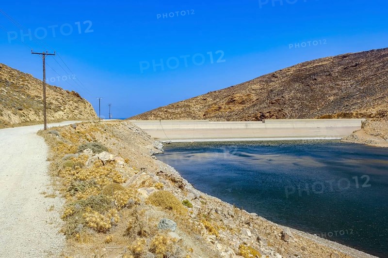 Mykonos, Cyclades, Greece - Dry Fokos Reservoir near Ano Mera. The Mykonos Municipal Water Supply and Sewage Management Company has two dams, Marathi Reservoir and Fokos Reservoir, to supply water to the island. Due to the prolonged drought, both are almost empty and are not being used