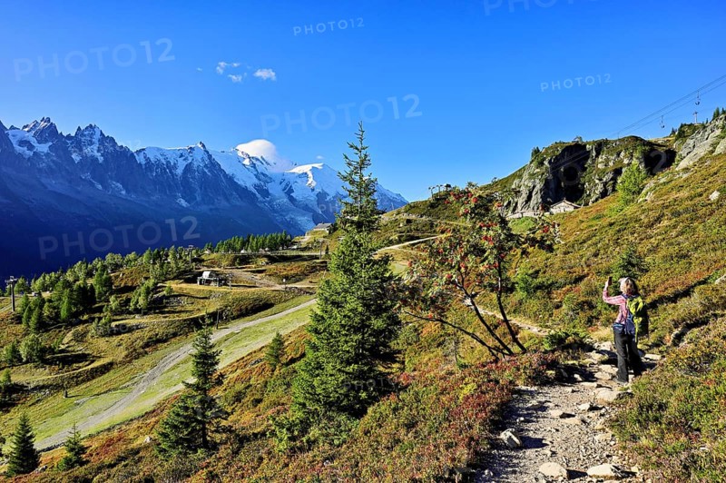Female hiker on a hiking trail with the La Flégère cable car mountain station and the snow-covered Mont Blanc massif, Chamonix-Mont-Blanc, Haute-Savoie, France