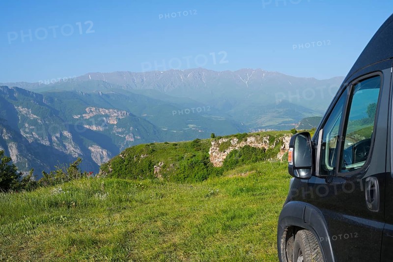 A van stands on a hill with a wide view of a green mountain landscape, camper near Halidzor, Syunik province, Caucasus, Armenia