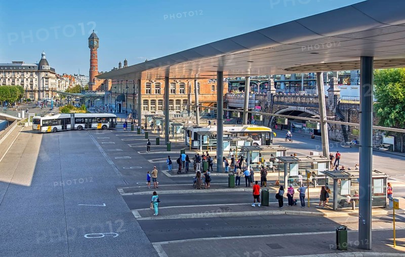 Commuters waiting for transit buses at bus stop of public transport company De Lijn at train station Gent-Sint-Pieters, Ghent, East Flanders, Belgium