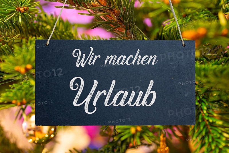 (Photo montage) Company holidays at Christmas: sign with the inscription WIR MACHEN URLAUB in front of a Christmas tree