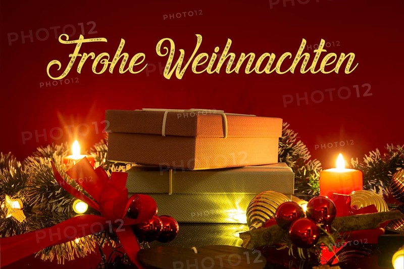 Christmas greetings: table with Christmas decoration and gifts against a red background with inserted lettering MERRY CHRISTMAS