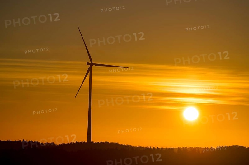 A single wind turbine in front of an intense orange sunset. The sky glows with bright colors, Swabian Jura, Baden-Württemberg, Germany