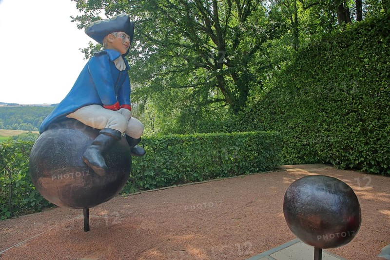 Baron von Münchhausen sculpture in the castle park, lying baron, uniform, blue, white, hat, cannonball, sitting, riding, bullets, castle, Lichtenwalde, Niederwiesa, Saxony, Germany