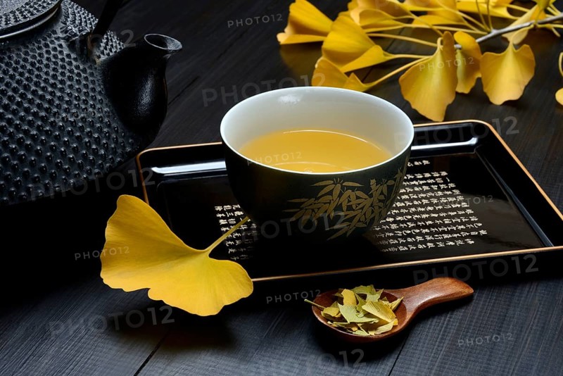 Ginkgo tea in tea bowl and ginkgo leaf, tea leaves in a spoon, ginkgo biloba