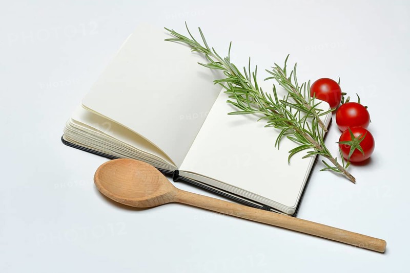 Blank notebook for cooking recipes, cooking spoon with rosemary sprig, tomato