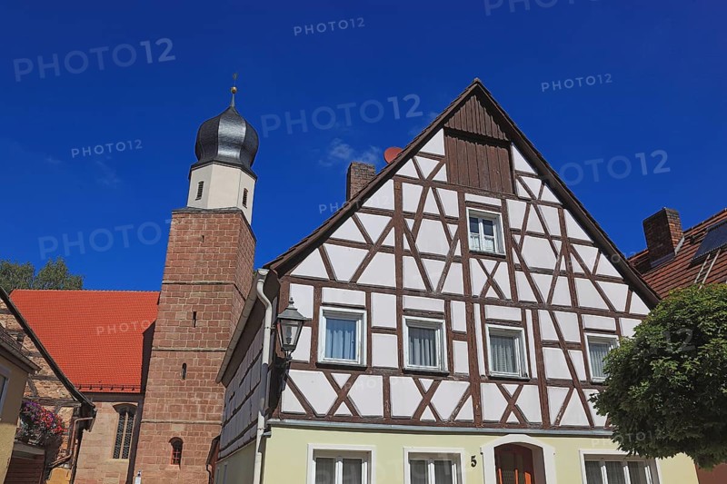 Half-timbered house and tower of the Catholic Church, town of Heideck in the district of Roth, Middle Franconia, Bavaria, Germany