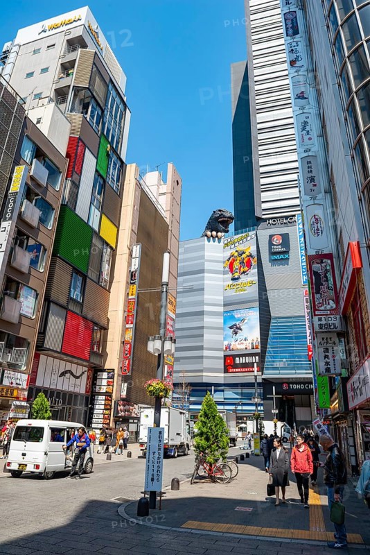Street scene with skyscrapers, figure Godzilla head on a skyscraper, Shinjuku City, Tokyo, Japan