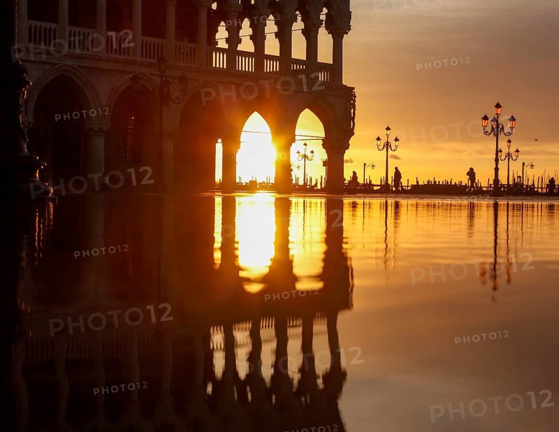 View through the arcades of the Doge's Palace at sunrise on Piazzetta during Acqua Alta, Venice, Veneto, Italy