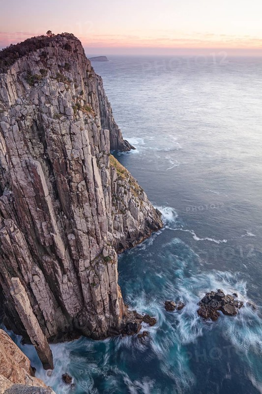 The Lanterns and Totem Pole Long exposure at sunrise shows glowing dawn over the dramatic cliffs of Cape Hauy. Waves hit the steep cliffs. Cape Hauy, Tasman Peninsula, Tasmania, Australia