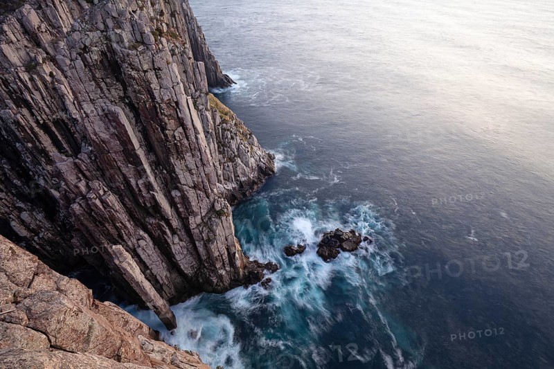 Totem Pole at The Lanterns. Long exposure at sunrise shows glowing dawn over the dramatic cliffs of Cape Hauy. Waves hit the steep cliffs. Cape Hauy, Tasman Peninsula, Tasmania, Australia