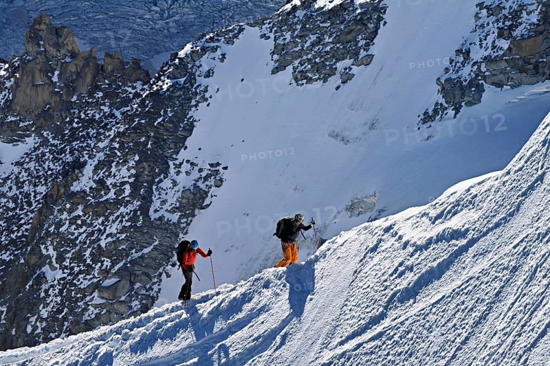 Two mountaineers run across a snow-covered mountain ridge, Aiguille du Midi, Chamonix-Mont-Blanc, Haute-Savoie, France