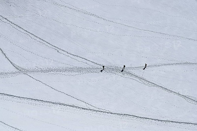 A group of mountaineers runs across a snow-covered mountain, Aiguille du Midi, Chamonix-Mont-Blanc, Haute-Savoie, France