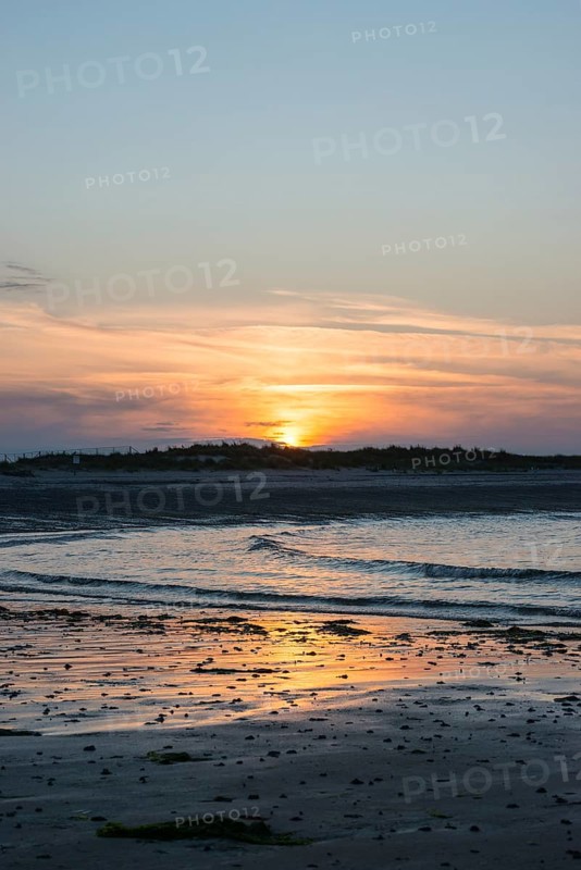 Sunset on a quiet beach with soft light on the waves, wet beach at low tide, dunes in the background, atmospheric, glowing, calm, warm atmosphere, reflecting light on water and beach, reflection, warm and cool tones, orange, yellow, gold, blue, gray, clouds, evening, shade, sandy beach, sand, shore, nobody, maritime, deserted, sea, waves, soft surf, swell, sea, swell, swell, sea, swell, swell, swell, sea, swell, swell, swell, swell, sea, Aade Bay, North Sea, Dune Island, Heligoland, Pinneberg District, Schleswig-Holstein, Germany