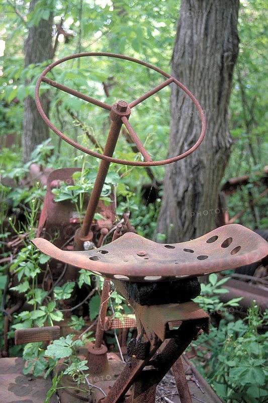 Rusted wheel and iron seat from an American tractor around 1900, deposited in a wooded area, Marksboro, New Jersey, USA