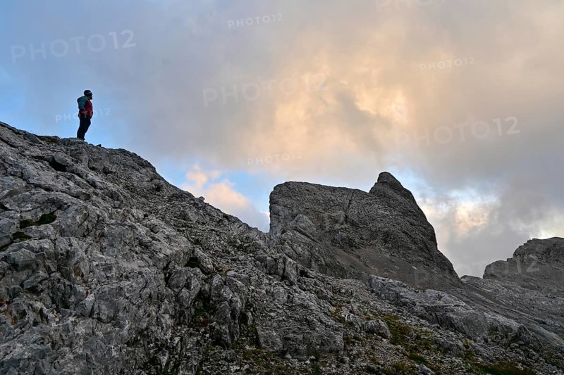 Mountaineer enjoys solitude in the Steinernes Meer with a view of the summit of Wildalmkirchl, Berchtesgaden Alps, Austria