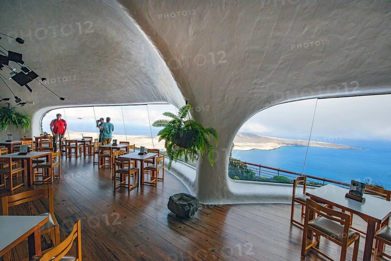 Interior of café with panoramic window in building designed by Cesar Manrique with the collaboration of Jesús Soto and architect Eduardo Caceres without right angles corners on viewpoint tourist attraction El Mirador del Río on the summit of the 474 meter high Risco de Famara in Famaramassiv with panoramic view of the Chinijo Archipelago, La Graciosa island, Lanzarote, Canary Islands, Canary Islands, Spain
