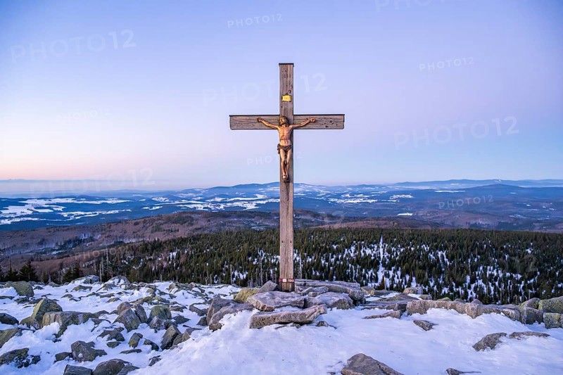 Christian cross on the peak of Mount Lusen with the view over the hills of the bavarian forest at sunrise at winter, Bavaria, Germany
