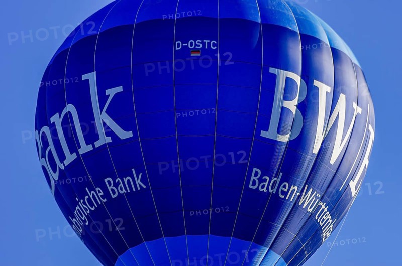 A hot air balloon, registration D-OSTC, rises into the air as part of an air show at the Rossfeld Air Sports Association's Flying Festival on Rossfeld in Metzingen-Glems, Baden-Württemberg, Germany, for editorial use only