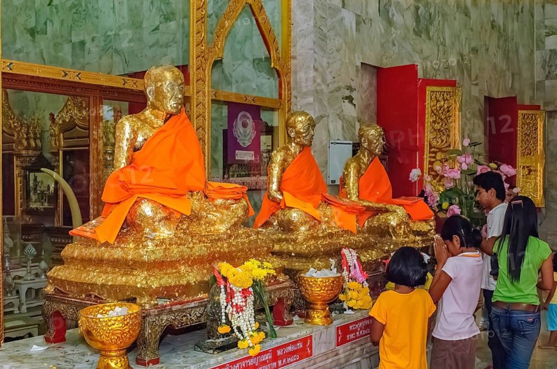 Buddhist believers Buddhists pray making offerings to statues of Buddhist monks covered with gold leaf at Wat Chalong Monastery, Wat Chaithararam, Phuket Island, Phuket Province, Thailand