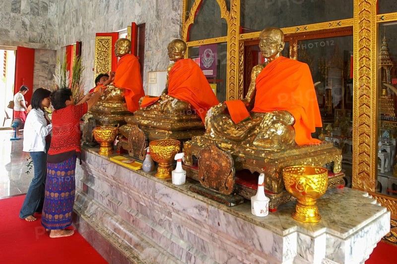 Buddhist believers Buddhists pray making offerings to statues of Buddhist monks covered with gold leaf at Wat Chalong Monastery, Phuket Island, Phuket Province, Thailand