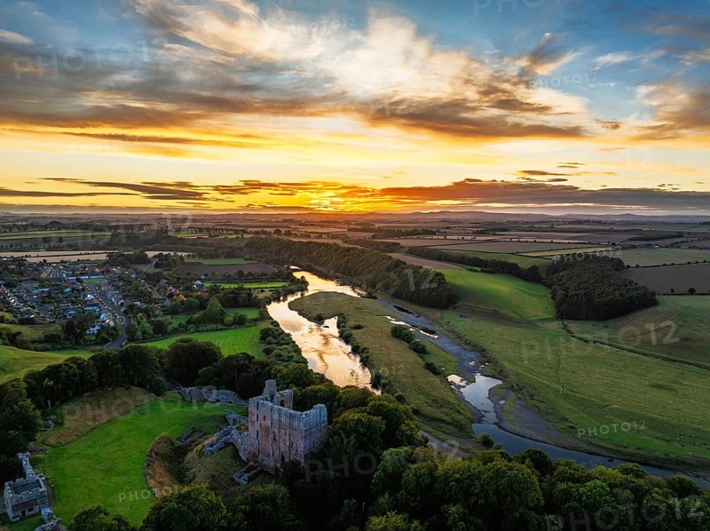 Sunset over Norham Castle and River Tweed from a drone, Norham, Northumberland, England, United Kingdom