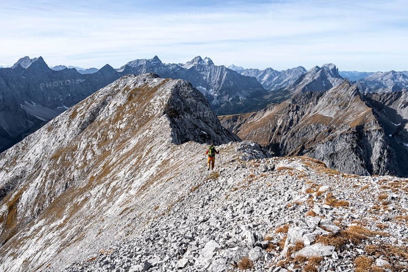 Hikers on the summit ridge of the Gamsjoch, behind rock faces of the Laliderer Spitze, eastern Karwendel, Tyrol, Austria