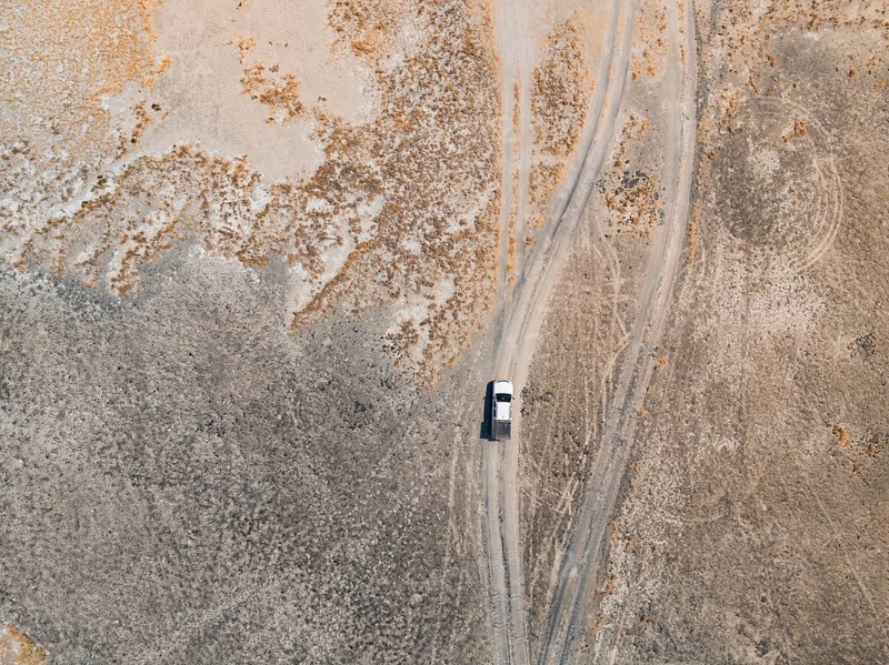 Aerial view, top-down view, off-road car driving on a salt pan, arid landscape, Botswana