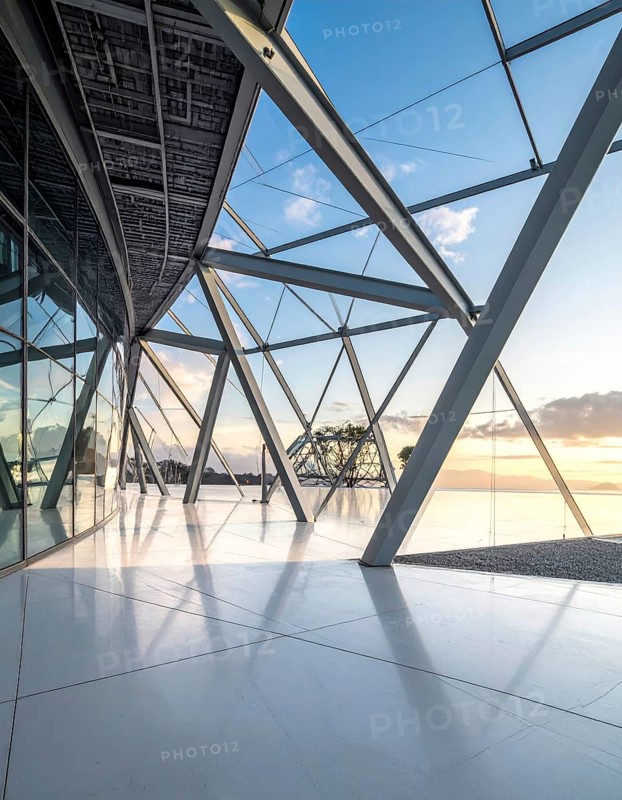 Modern architectural framework with glass and steel structure, glass facade with a greed of steel arrows, blue sky with a soft golden light of a sunrise, AI generated