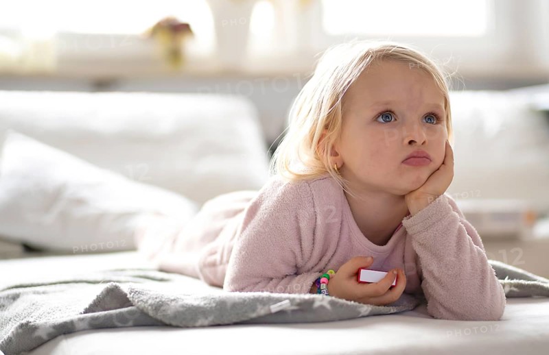 Child, girl, 4 years, blonde, lying on sofa, watching TV, watching television, watching television, excited, Stuttgart, Baden-Württemberg, Germany