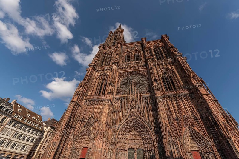 Strasbourg's Notre Dame Cathedral stands majestically there. Its magnificent architectural details are clearly visible under the blue, cloudy sky. Bas Rhin, Alsace, France