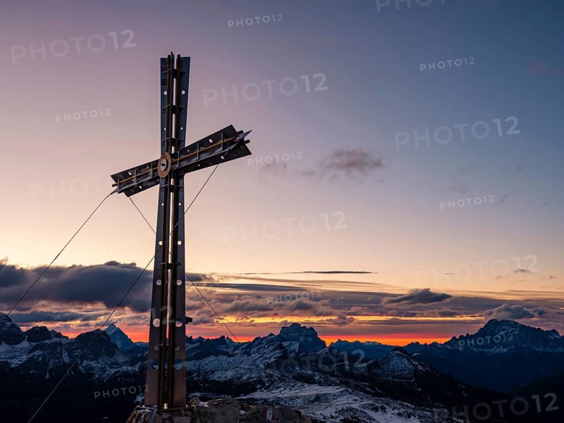 Sassongher summit cross at sunrise, in the background Monte Cristallo, Monte Pelmo and Civatta, Dolomites, Trentino, South Tyrol, Italy