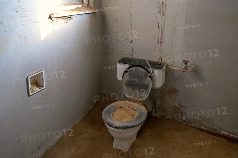 Toilet full of sand in the former hospital, Kolmanskop, restricted diamond area, Karas region, Namibia