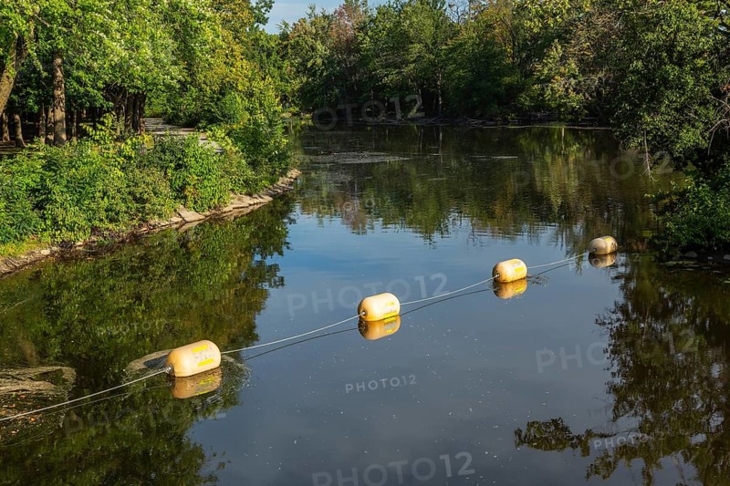 String of yellow cautionary navigation marker buoys on water surafce of river serving to warn, signal or indicate of a hazard beyond, Terrebonne, Quebec, Canada