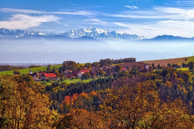 Village of Juriens in the Vaud Jura with view of Mont Blanc, haze over Lake Geneva, autumn-coloured deciduous trees in front, Canton of Vaud, Switzerland