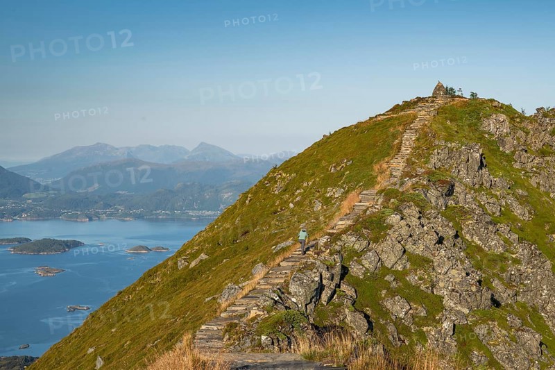 Woman with hiking poles walking up Rørsethornet stone stairs, with 3292 steps one of the longest continuous stone stairs in the world, Sherpat stairs or Midsund stairs or Midsundtrappene, Rørsethornet hike, Otroya or Otrøya island, Møre og Romsdal, Norway