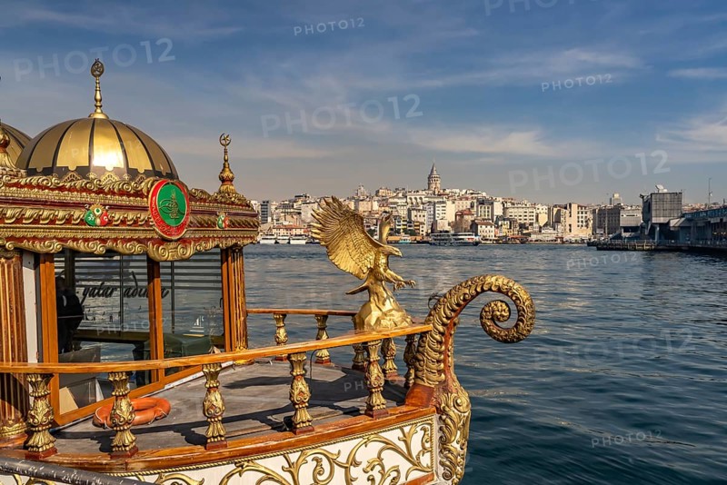 Golden oriental restaurant ship on the banks of Eminönü, Beyoglu and the Galata Tower, Istanbul, Turkey