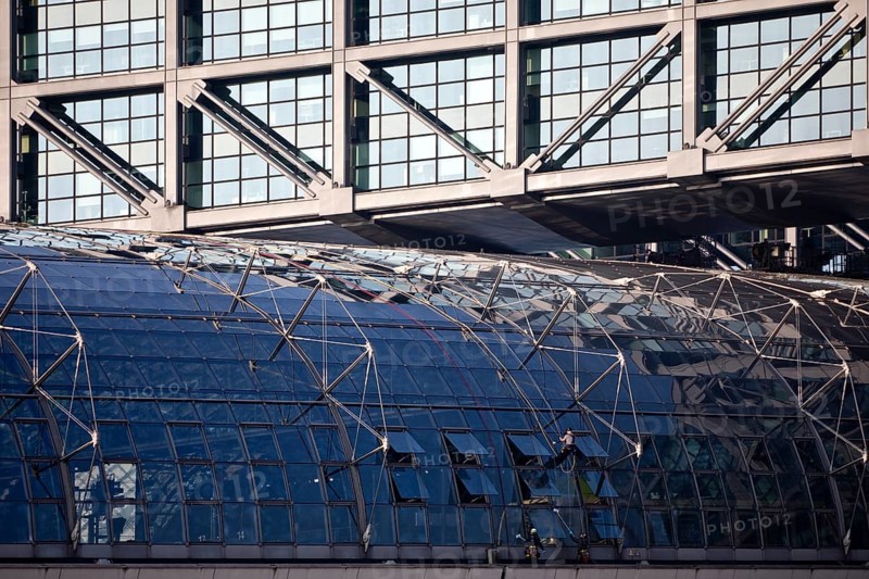 Three male glass cleaners cleaning a glass roof at Berlin Central Station, Berlin, Germany