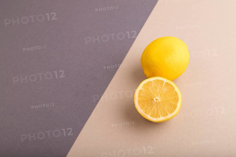 Yellow Lemon Cut in half on beige and gray pastel paper background. Side view, copy space. healthy food, vegetable, minimalism
